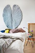 Hand-sewn leaf-shaped wall hanging above head of double bed