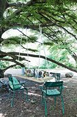 DIY table top suspended from tree and turquoise garden chairs