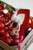 Stag figurine and red Christmas decorations in wooden crate