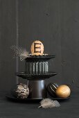 Easter arrangement of feathers and painted eggs on black cake stand