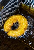 A churro in a deep fat fryer with oil