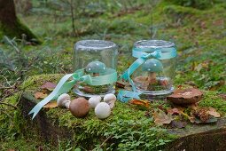 Painted wooden toadstools under upturned mason jars decorated with ribbons in woods