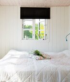 Kleines, weißes Schlafzimmer mit Fenster zum Sommergarten