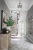 Wooden staircase, gallery of photos, cabinet and marbled tiled floor in elegant country-house hallway