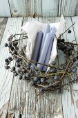Blue candles and paper in wreath of sloe branches