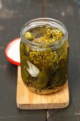 Gherkins in a glass jar on a chopping board