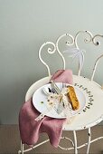 East Friesian cutlery tied together with lace ribbon on a porcelain plate on vintage metal chair