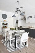 Dining table on grey and white striped rug in grey and white kitchen