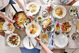 Gedeckter Tisch mit Spaghetti, Tomaten und Parmesan