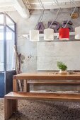 Schlichter Edelholztisch mit Holzbänken in rustikalem Ambiente mit Designer-Leuchten