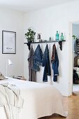 Clothes hooks below black wall-mounted shelf in bedroom