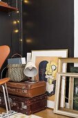 Picture frames and stacked vintage suitcases against black wall