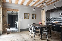 Oval table and classic chairs in front of kitchen counter built into large niche in wall