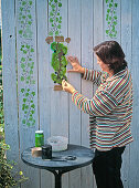 Painting a wooden wall with ivy using a stencil