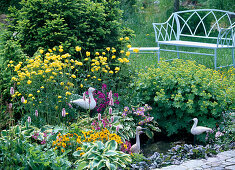 Bench and side table behind mini-pond in herbaceous border