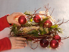 Adventskranz mit roten Kugeln, Zweigen und Efeu (5/6)