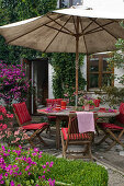 Terrasse am Haus mit Holz-Sitzgruppe und Sonnenschirm