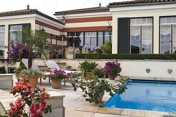 Mediterranes Flair: Swimmingpool eingelassen in Terrasse mit Kübelpflanzen