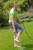 Woman cooling her feet with the garden hose