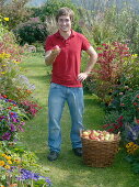 Young man with freshly harvested apples in a wicker basket
