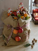 Basket with apples (Malus) and oranges (Citrus sinensis) in jute bag