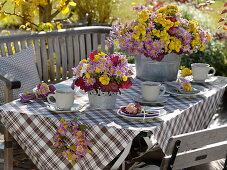 Herbstliche Tischdeko mit Herbstchrysanthemen und Heuchera-Blättern