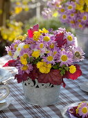 Herbstliche Tischdeko mit Herbstchrysanthemen und Heuchera-Blättern