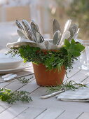 Herbs around clay pot with cutlery wreath