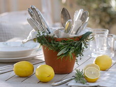 Wreath of herbs around a clay pot with cutlery