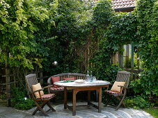 Kleine gepflasterte Terrasse mit hölzernen Möbeln