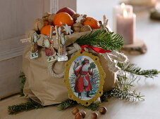 Paper bag with Father Christmas wafers, filled with mandarins (citrus), nuts