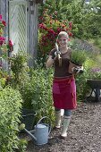 Junge Frau mit Spaten und Lavendel vor Gartenhaus