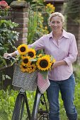 Frau mit Fahrrad und Sonnenblumen