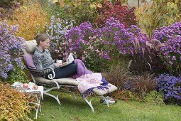 Lie on the autumnal bed with asters and grasses