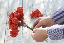 Lampion flowers bouquet in wreath of ivy, clematis and rosehips