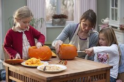 Mother with daughters making pumpkin heads