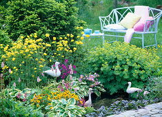 Bench and side table behind mini pond in shrub bed