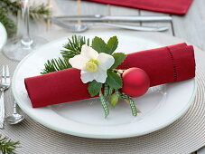 Rote Serviette weihnachtlich dekoriert mit Helleborus (Christrose)