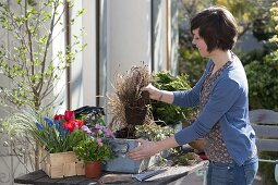 Frau bepflanzt Kasten im Frühling neu (2/6)