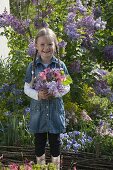 Girl with bouquet of Aquilegia (columbine) and Syringa (lilac)