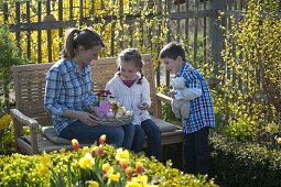 Frau und Kinder mit Osternest im Bauerngarten