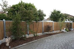 Asian border with shrubs, bark mulch and fence made of bamboo elements