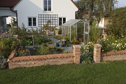 Small cottage garden with wall and greenhouse