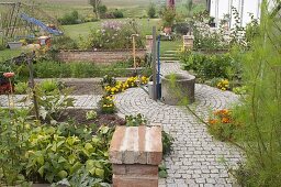 Paved path in a cottage garden with fountain and circle in the middle