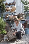 Young woman cleaning basket with brush, baskets hung on wall and on table