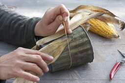 Covering a tin pot with corn leaves (2/3)