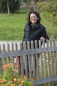 Woman behind garden fence, Tropaeolum (nasturtium)