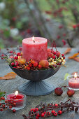 Kerze in Schale mit Beeren und Wildfrüchten