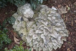 Moss-covered cement figure: sleeping child in a bed of leaves