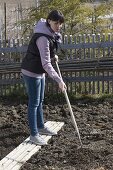 Woman loosening the soil in spring to prepare for sowing